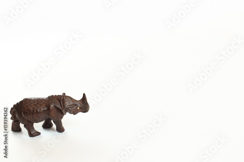 Hand carved wooden rhinoceros standing looking right isolated on white background 