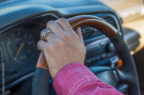 Man's hand on the steering wheel inside of a car © allenkayaa