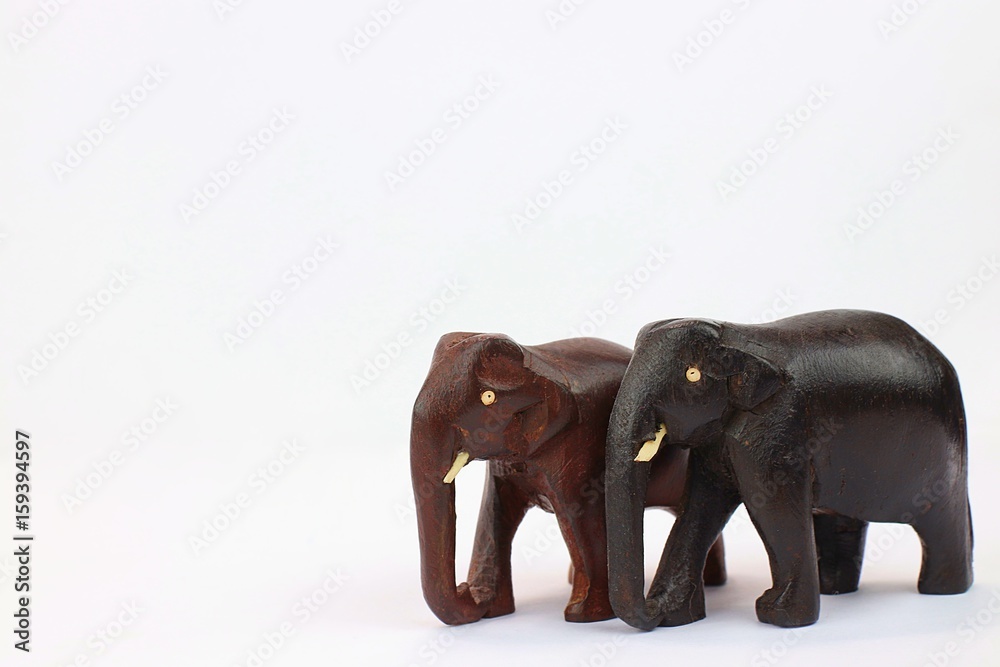 Close up of hand carved wooden elephants standing together isolated on white background 