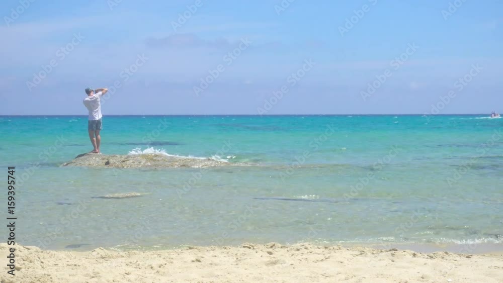 Man Taking Pictures with Smartphone on a White Wild Mediterranean Sea Beach in Italy Man Taking Pictures with Smartphone on a White Wild Mediterranean Sea Beach in Italy