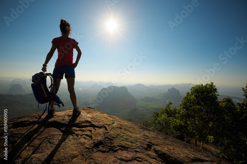 young woman hiker enjoy the view on sunrise mountain top rock