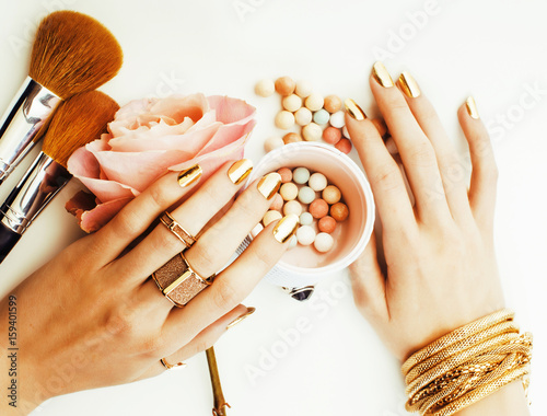 Fotografie woman hands with golden manicure and many rings holding brushes,