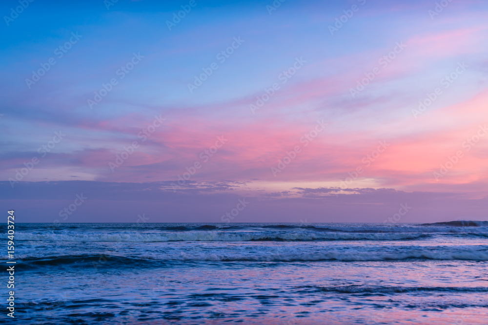 Colored ocean waves at sunset time. Amazing beautiful sky, long exposure waves for background. Panorama of beautiful sunset on the ocean. Beach pattern. Surfing Waves, Tropical Beach. Panoramic Sunset