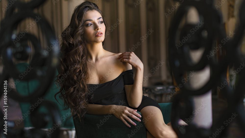 Fototapeta premium The image of a beautiful luxurious woman sitting on a vintage couch
