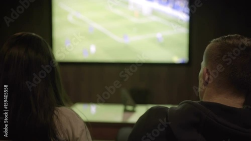 Man and woman watching football on the big screen close-up