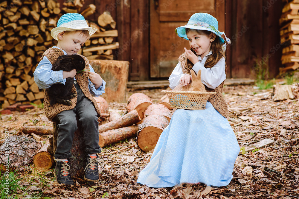 Fototapeta premium little boy and girl playing with rabbit in village
