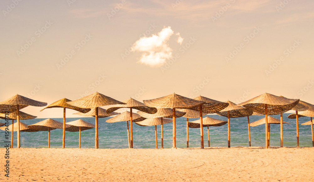 Straw umbrella rows on the sea shore