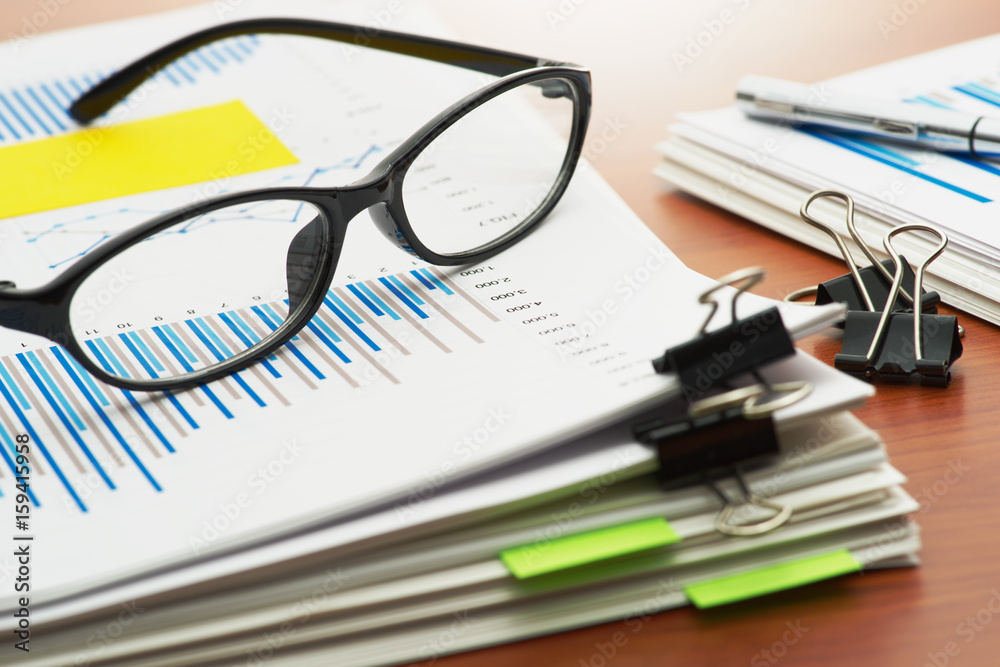 Paperwork. Pile of documents. Scanning reports. Pile of documents with blue chart and glasses on wooden desk.
Paperwork. Pile of documents. Scanning reports. Pile of documents with blue chart and glasses on wooden desk.