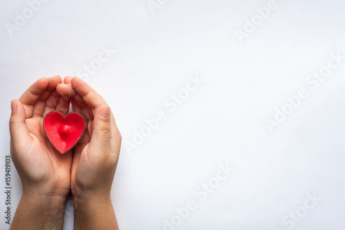Red Heart Shape On Child Hands On White Paper Background Close Up.
