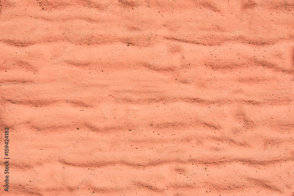 A wall with a rough surface is painted in pink