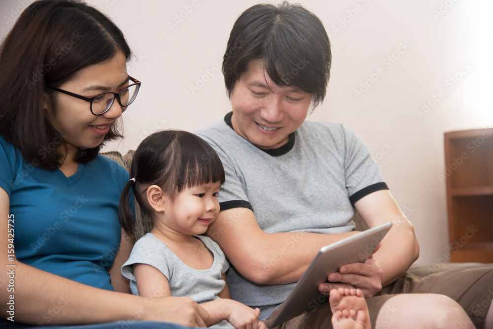 Happiness of Asian  family sitting and playing digital tablet.