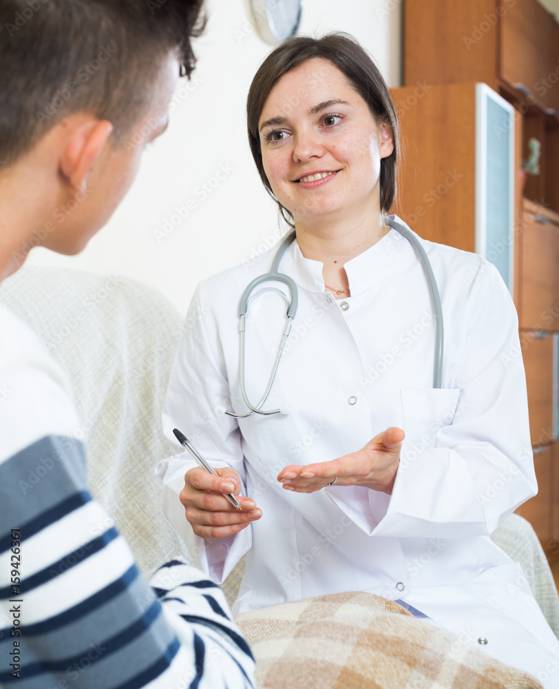 Fototapeta premium Doctor examinating teen boy with quinsy at home