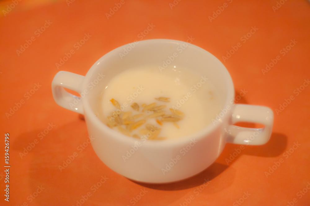 Mushroom cream soup in white bowl isolated on yellow orange table as background Mushroom cream soup in white bowl isolated on yellow orange table as background