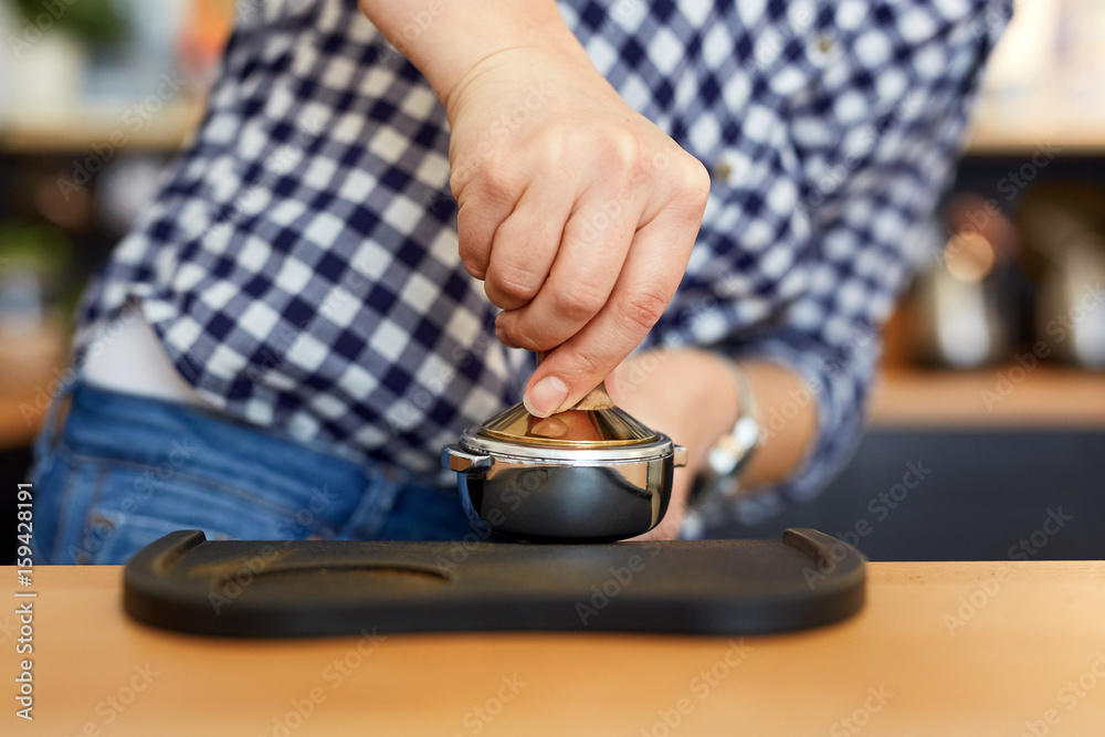 Female barista tamping fresh ground coffee