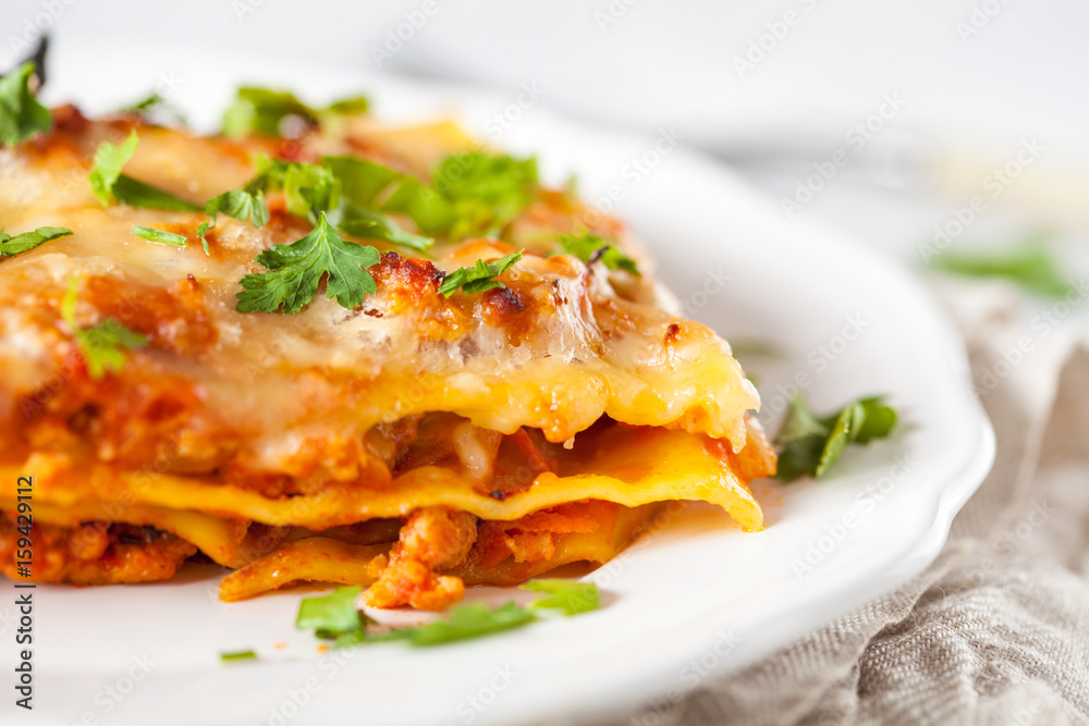Piece of traditional Italian meat lasagna on a white plate. Piece of traditional Italian meat lasagna on a white plate.