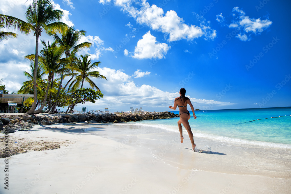 Young woman running at the tropical beach