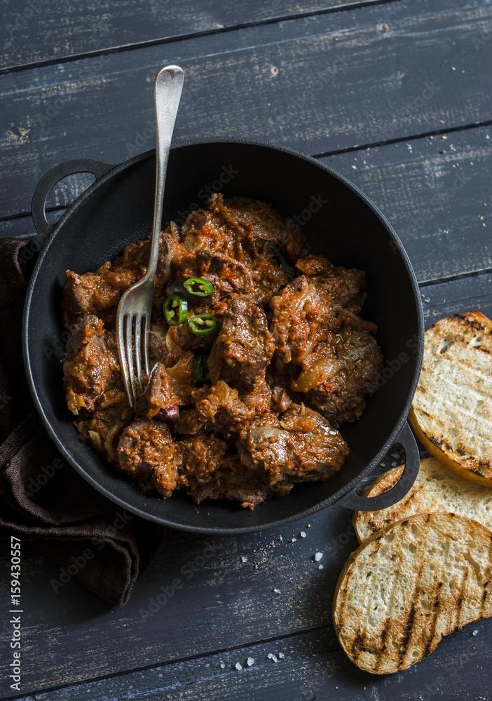 Easy peri-peri chicken livers in a cast iron skillet on a dark background, top view. Simple rustic lunch Easy peri-peri chicken livers in a cast iron skillet on a dark background, top view. Simple rustic lunch