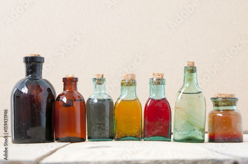 Many antique glass bottles with colored liquids close up. For the pharmacy, oil, cosmetics.