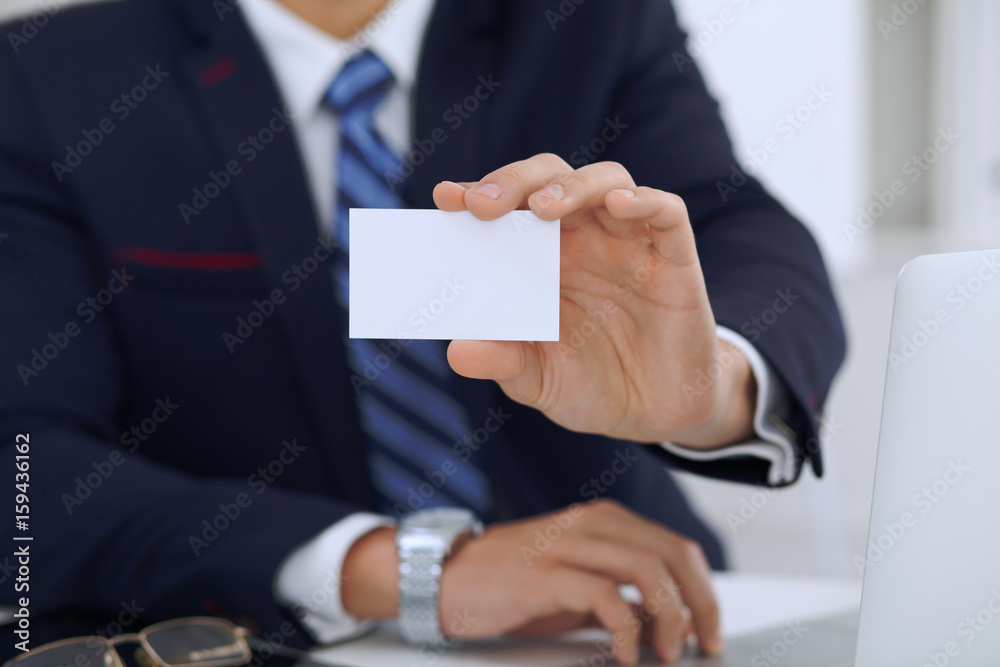 Close up of businessman or lawyer giving a business card while sitting at the table. He offering partnership and success deal Close up of businessman or lawyer giving a business card while sitting at the table. He offering partnership and success deal
