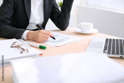 Business woman  is sitting at the table and working in  white colored office. photo