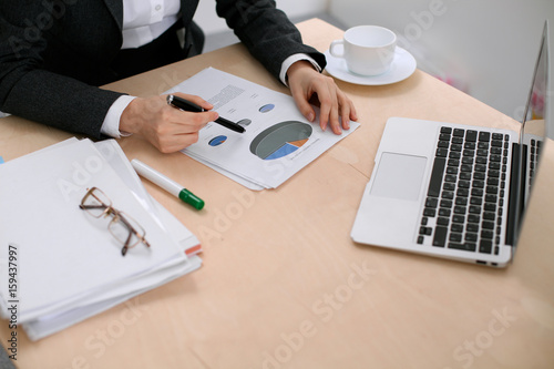 Business woman sitting at the table and examines the financial results photo