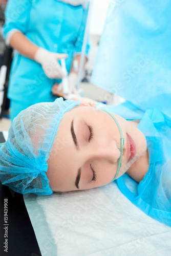 Vertical close up portrait of a young woman undergoing surgery at the hospital medical nurse making an injection on the background copyspace healthcare medical concept.