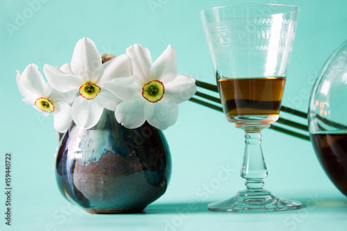 Fotografie Romantic date. Cognac or brandy. White daffodils in vintage vase.