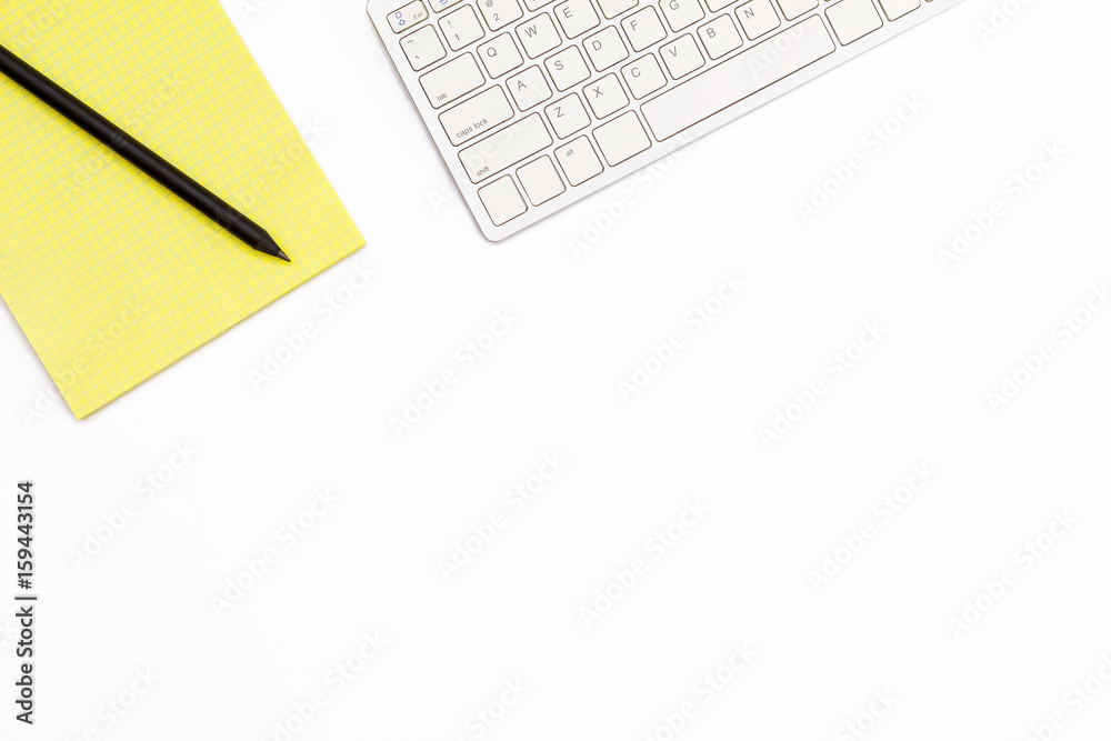 yellow Notepad, computer keyboard and black pencil on a white background. Minimal business concept of working place in the offices yellow Notepad, computer keyboard and black pencil on a white background. Minimal business concept of working place in the offices