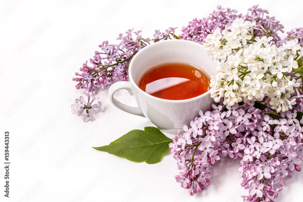 Cup of black tea with a bouquet of lilac on a white table Cup of black tea with a bouquet of lilac on a white table