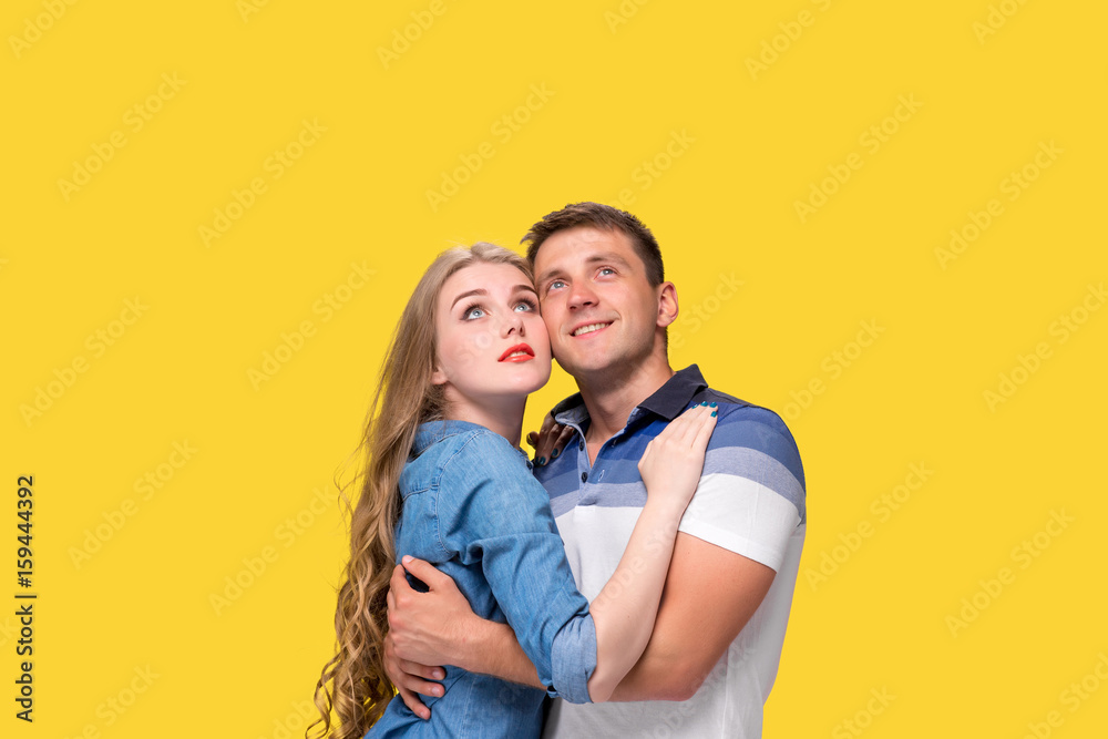 Portrait of a young couple standing against yellow background Portrait of a young couple standing against yellow background
