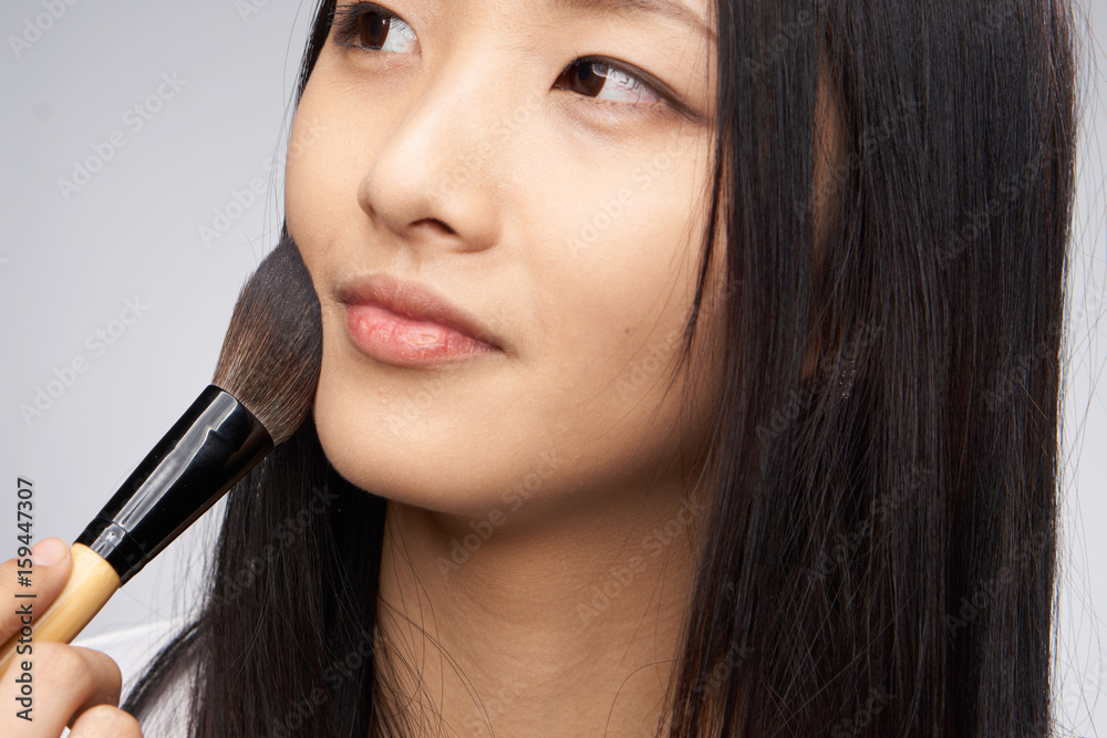 Woman with a cosmetic brush on a light background portrait Woman with a cosmetic brush on a light background portrait