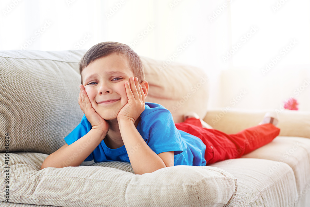 Curious small boy lying at living room on sofa Curious small boy lying at living room on sofa