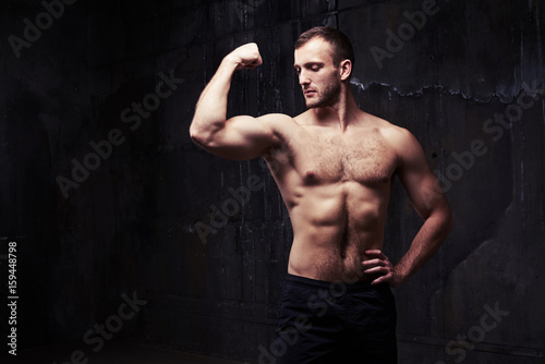 Shirtless man flexing muscles showing great relief of his arms and torso