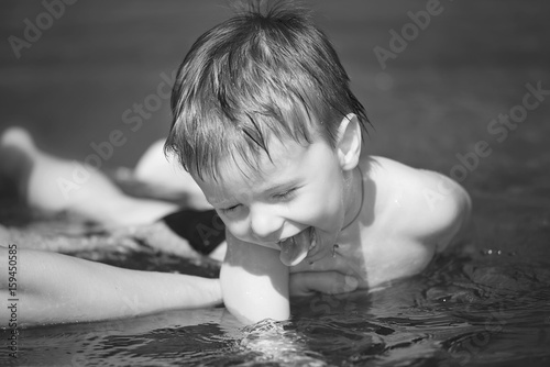 little boy with a smile on my face to learn how to swim in mother's arms black and white image