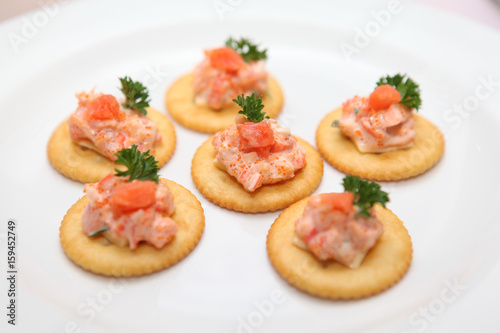 Cracker with fish eggs and salmon on white plate-selective focus