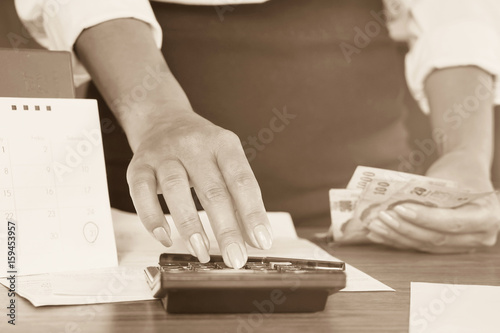 business woman hand calculating her monthly expenses during tax season and keep some money for her debt