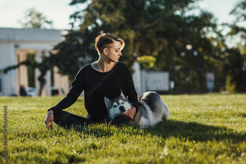 Fototapeta premium Beautiful young woman meditates with funny husky dog outdoors at park 
