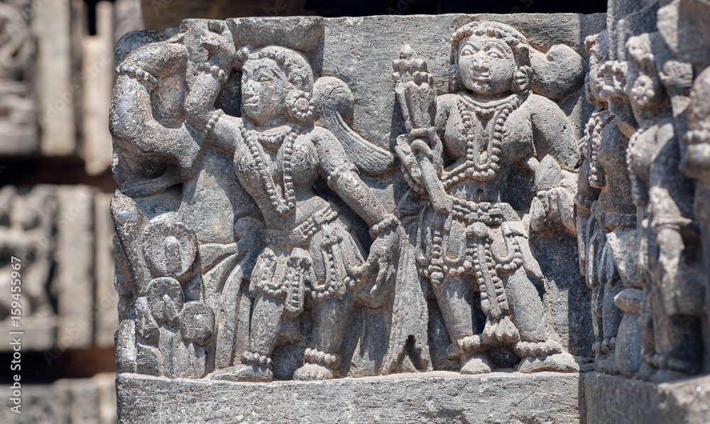 Women in traditional fashion style on relief of the historical building of India. Interior of 12th century Hoysaleshwara temple in Halebidu, Karnataka state.