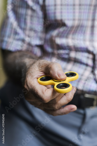 old man playing with a fidget spinner photo