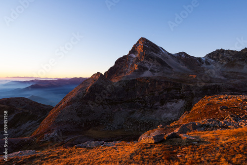 Alpine meadow and pasture set amid high altitude mountain range at sunsets. The Italian Alps, famous travel destination in summertime.