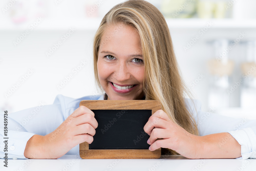 Junge blonde Frau hält Tafel vor sich Junge blonde Frau hält Tafel vor sich