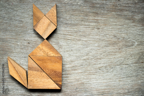 Tangram puzzle in cat shape on wooden background
