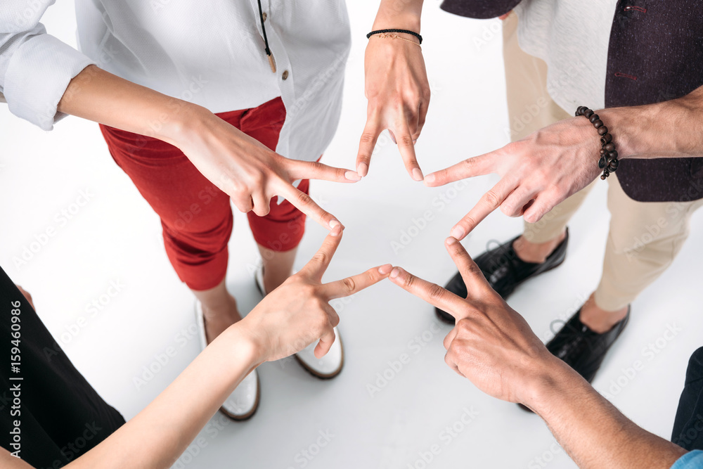 cropped shot of young friends gathered hands in form of star