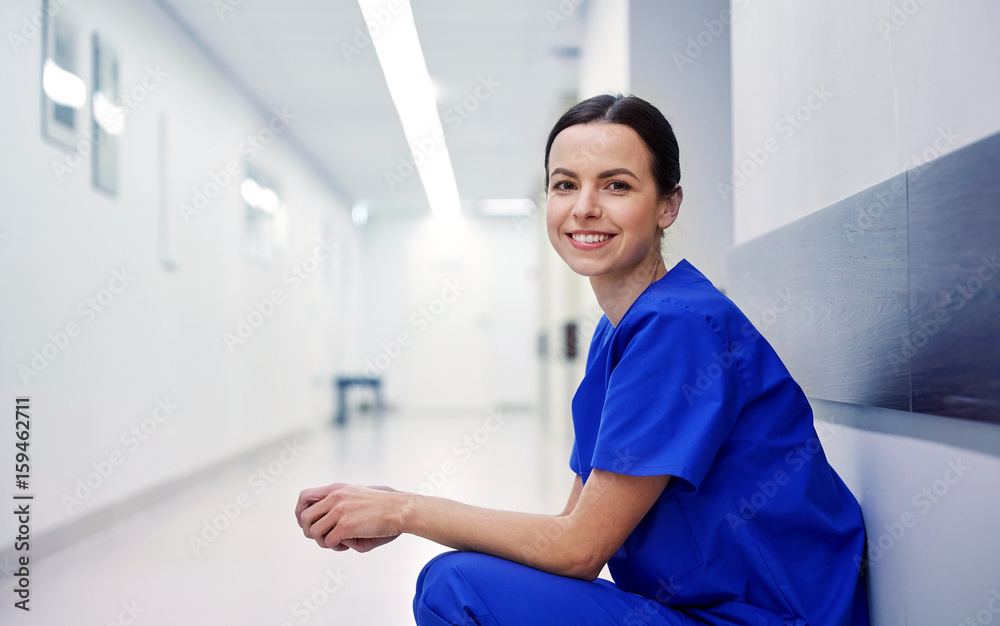smiling female nurse at hospital corridor - obrazy, fototapety, plakaty 