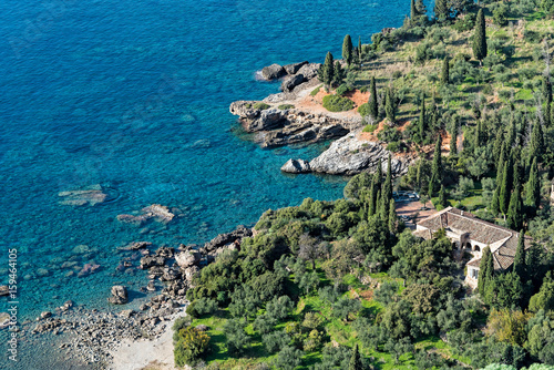 Typical mediterranean landscape with traditional house, olive trees, cypresses and blue sea in Peloponnese, Greece