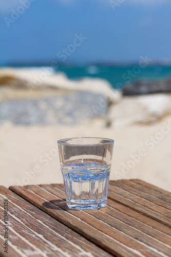 glass of water on wooden table in the beach