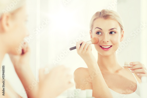 woman with makeup brush and powder at bathroom