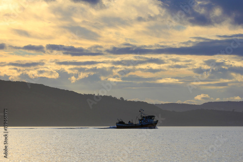 Carrier ship at sunset in the sea, Chiloe Island, Chile, South America