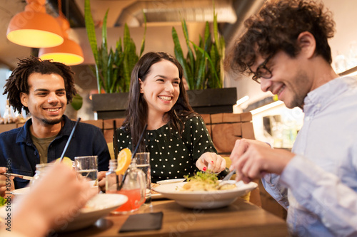 happy friends eating and drinking at restaurant