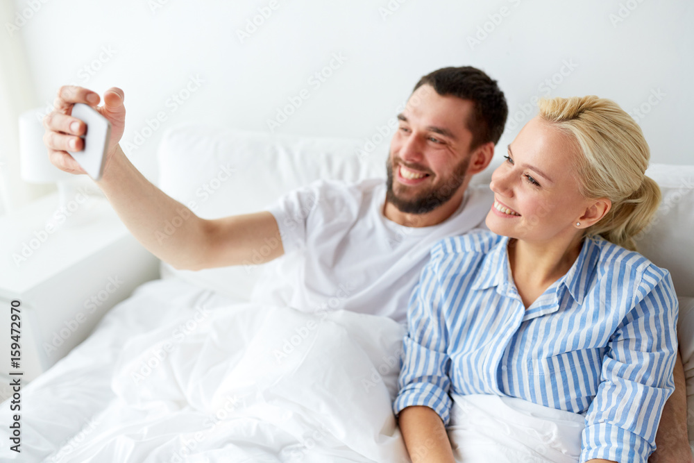 happy couple with smartphone taking selfie at home
